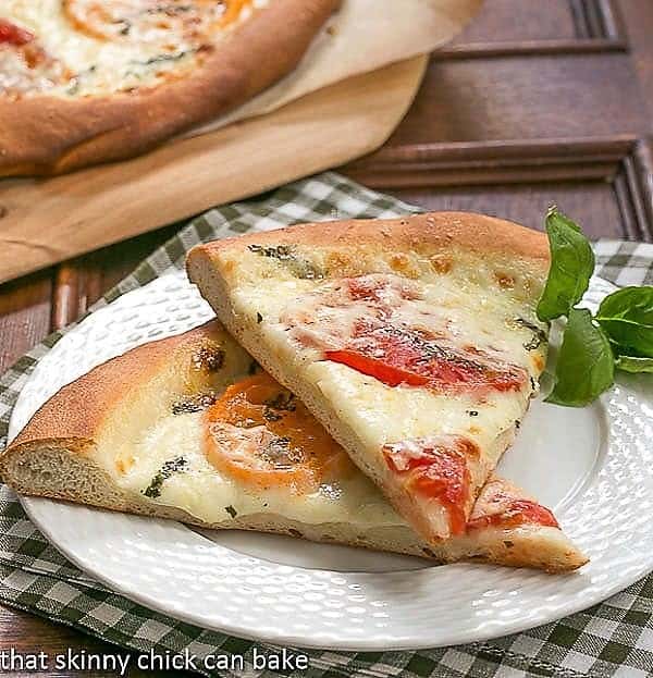 Homemade Pizza Margherita slices on a white plate.