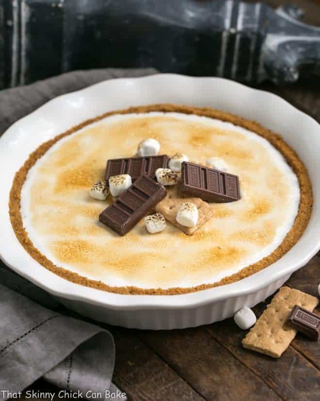 S'mores Pie topped with chocolate candy and mini marshmallows in a white pie plate
