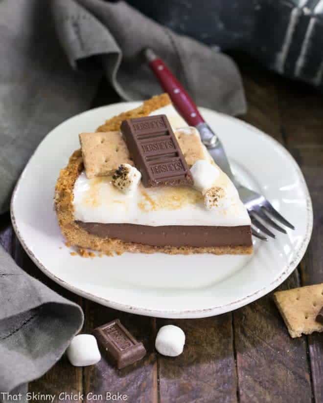 A slice of S'mores Pie on a dessert plate with a red handled fork