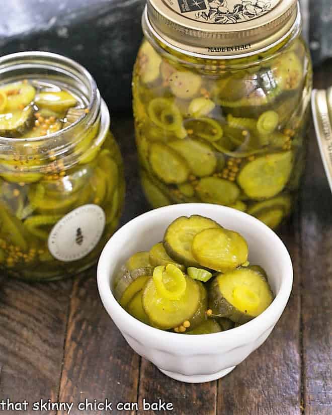 Two jars of Easy Bread and Butter Pickles plus a white bowl filled with pickle slices