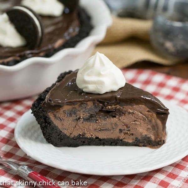 Fudge Topped Chocolate Ice Cream Pie slice with a dollop of whipped cream on a white dessert plate.