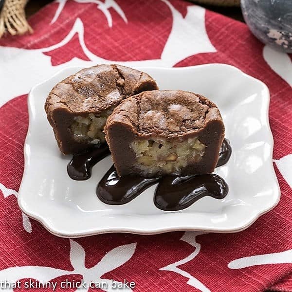 German Chocolate Brownie Cupcakes on a white dessert plate drizzled with fudge sauce.