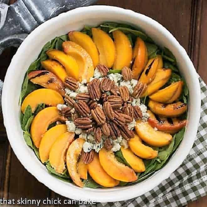 Overhead view of a bowl of Spinach Salad with Grilled Peaches and Blue Cheese