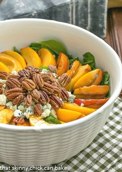 Spinach Salad with Grilled Peaches and Blue Cheese in a white textured serving bowl