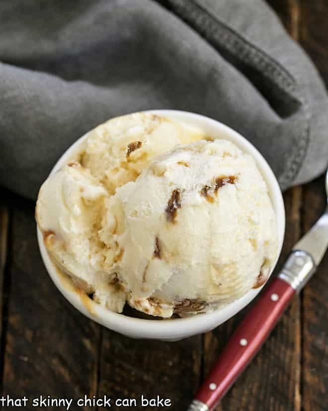 Overhead view of a white bowl of Vanilla Caramel Swirl Ice Cream with a red handle spoon.