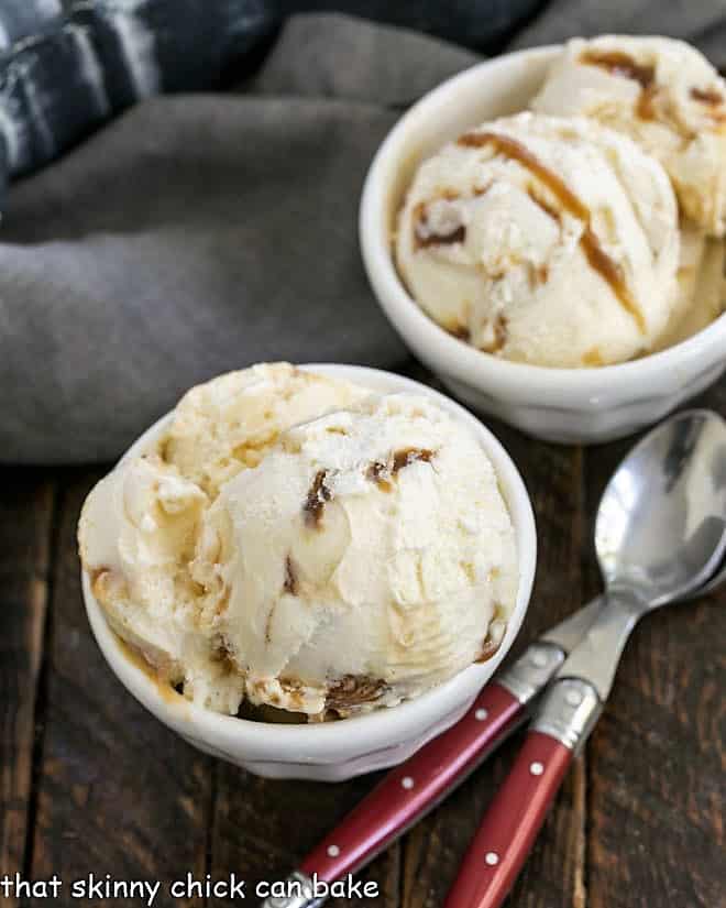 2 bowls of Vanilla Caramel Swirl Ice Cream with 2 red handled spoons.