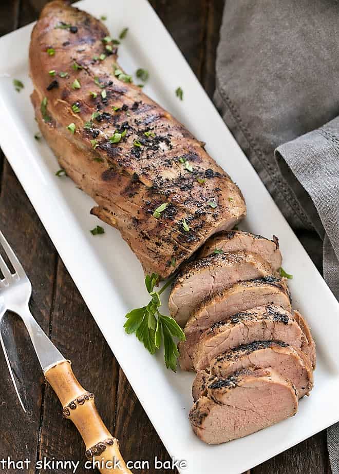 Grilled pork tenderloin on a rectangular white platter