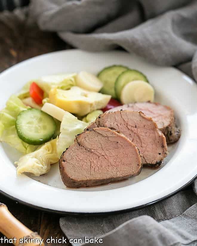 Whiskey Marinated Pork Tenderloin with a green salad on a white plate.