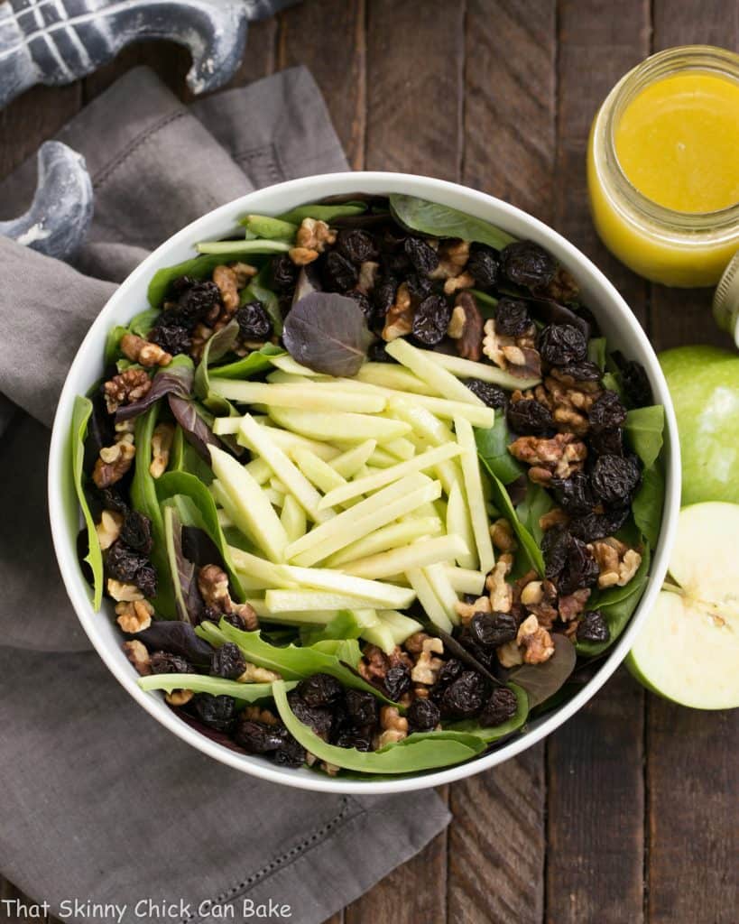 Apple, Cherry, Walnut Salad with Maple Dressing overhead view with halved apple and dressing in a jar