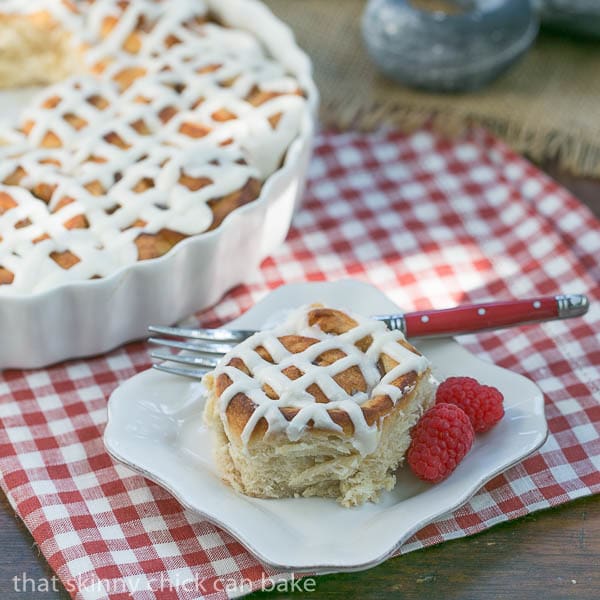 Apple Cinnamon Rolls in a baking dish and one on a small white plate with a red handled fork