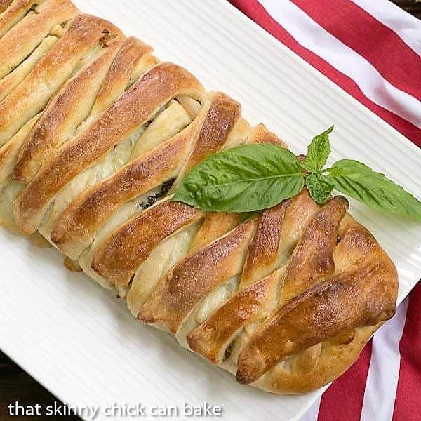 Overhead view of a braided stromboli on a white platter.