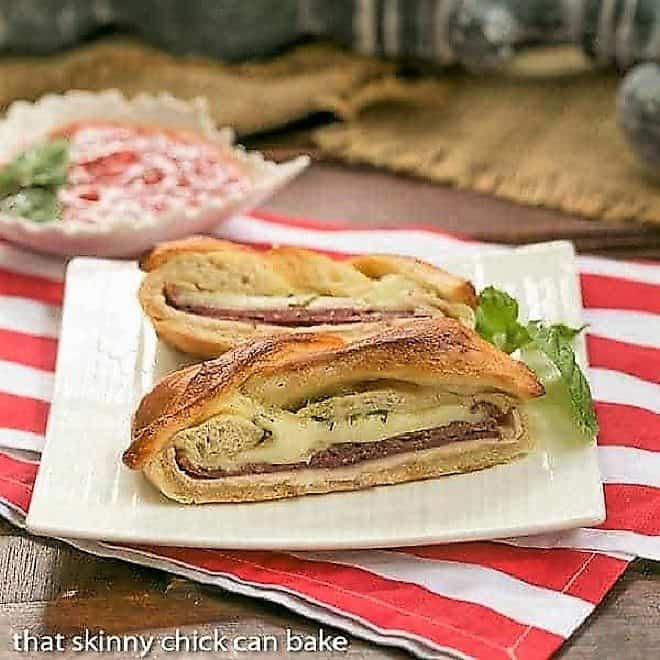 Braided Stromboli on a square white plate with a sprig of basil.