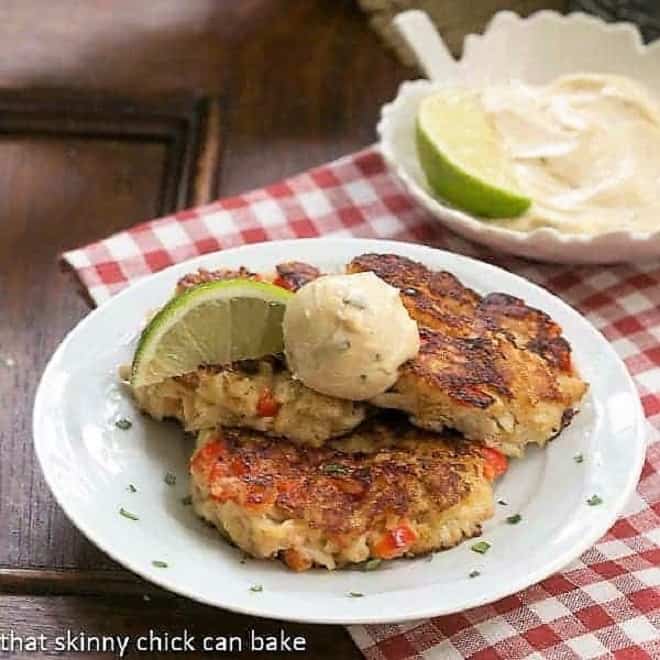 Crab Cakes on a round white plate with lime and aioli