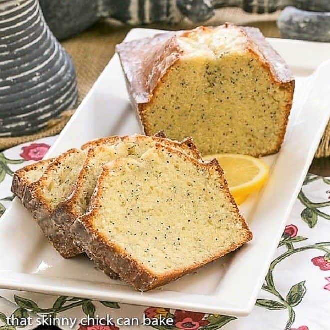 Slices of Glazed Poppy Seed Bread and half a loaf on a white ceramic tray