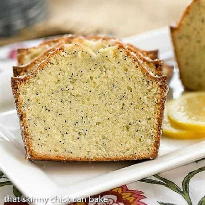 Glazed Poppy Seed Bread slices on a white tray with lemon slices