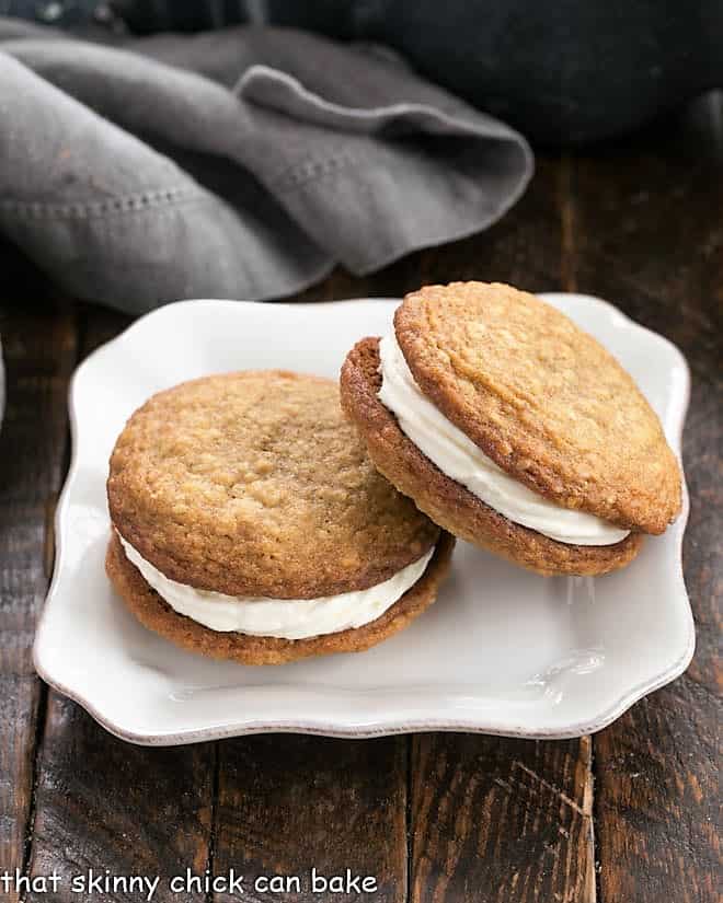 One oatmeal creme pie leaning on another on a square white plate