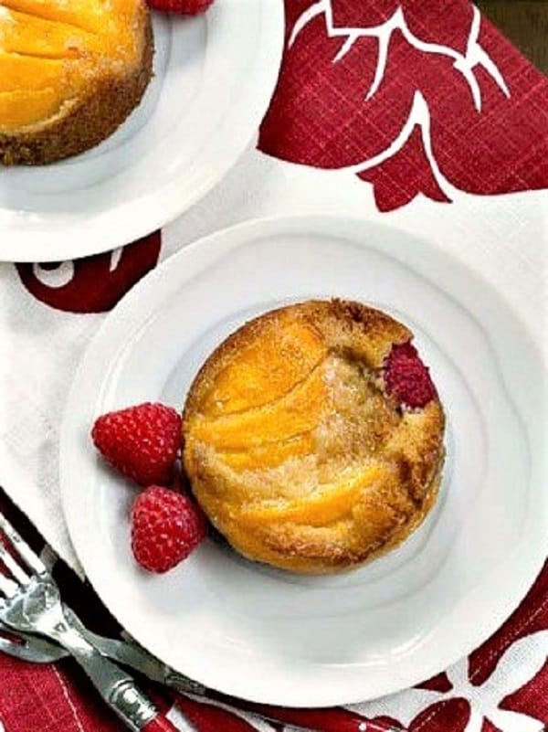 Overhead view of Oven Roasted Peach Cakes on white plates over a red and white napkin.