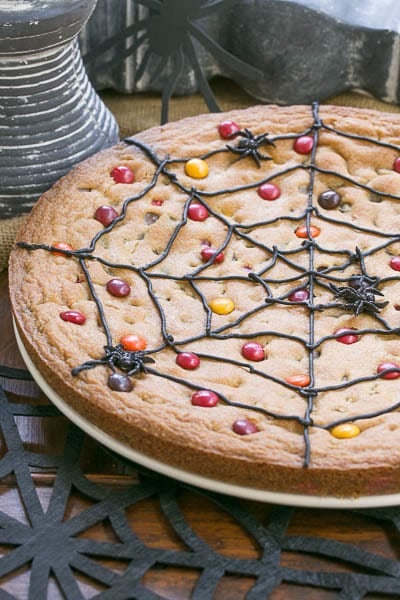 Spiderweb Cookie Cake on a white plate over a black felt spiderweb.