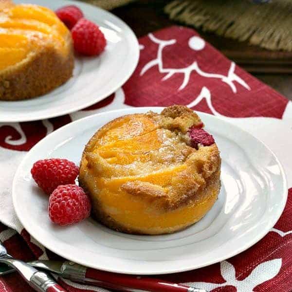 Oven Roasted Peach Cakes on white dessert plates with fresh raspberries.