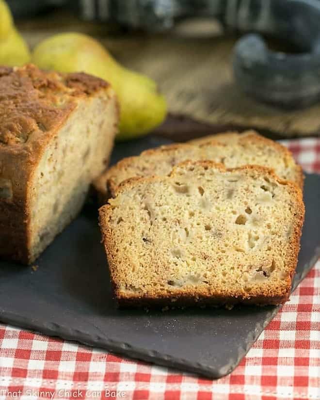 Sour Cream Pear Bread - A delectable autumn quick bread with subtle warm spices and chunks of fresh pears Sour Cream Pear Bread slices on a slate cutting board.