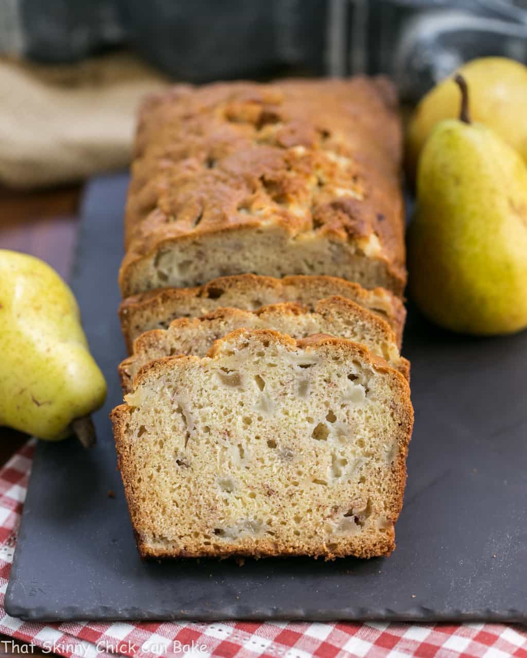 Sour Cream Pear Bread - A delectable autumn quick bread with subtle warm spices and chunks of fresh pears Sliced Sour Cream Pear Bread with whole pears on a slate tray.