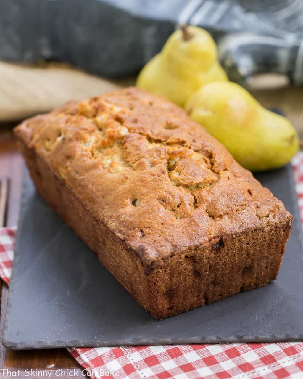 Sour Cream Pear Bread - A delectable autumn quick bread with subtle warm spices and chunks of fresh pears Loaf of Sour Cream Pear Bread on a slate board.