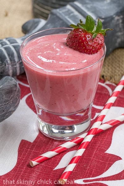 Berry Smoothies in a short glass with a berry garnish and two straws