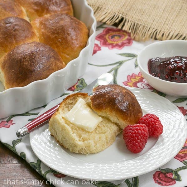 Brioche Dinner Rolls on a white plate with a pat of butter.