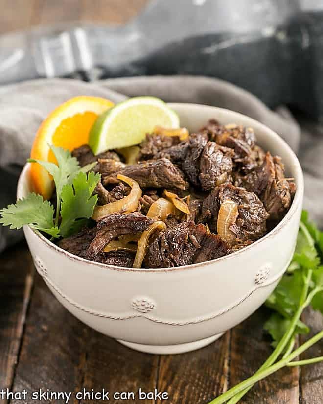  Scrumptious Cuban Shredded Beef 45 degree angle view in a white bowl with a sprig of cilantro.