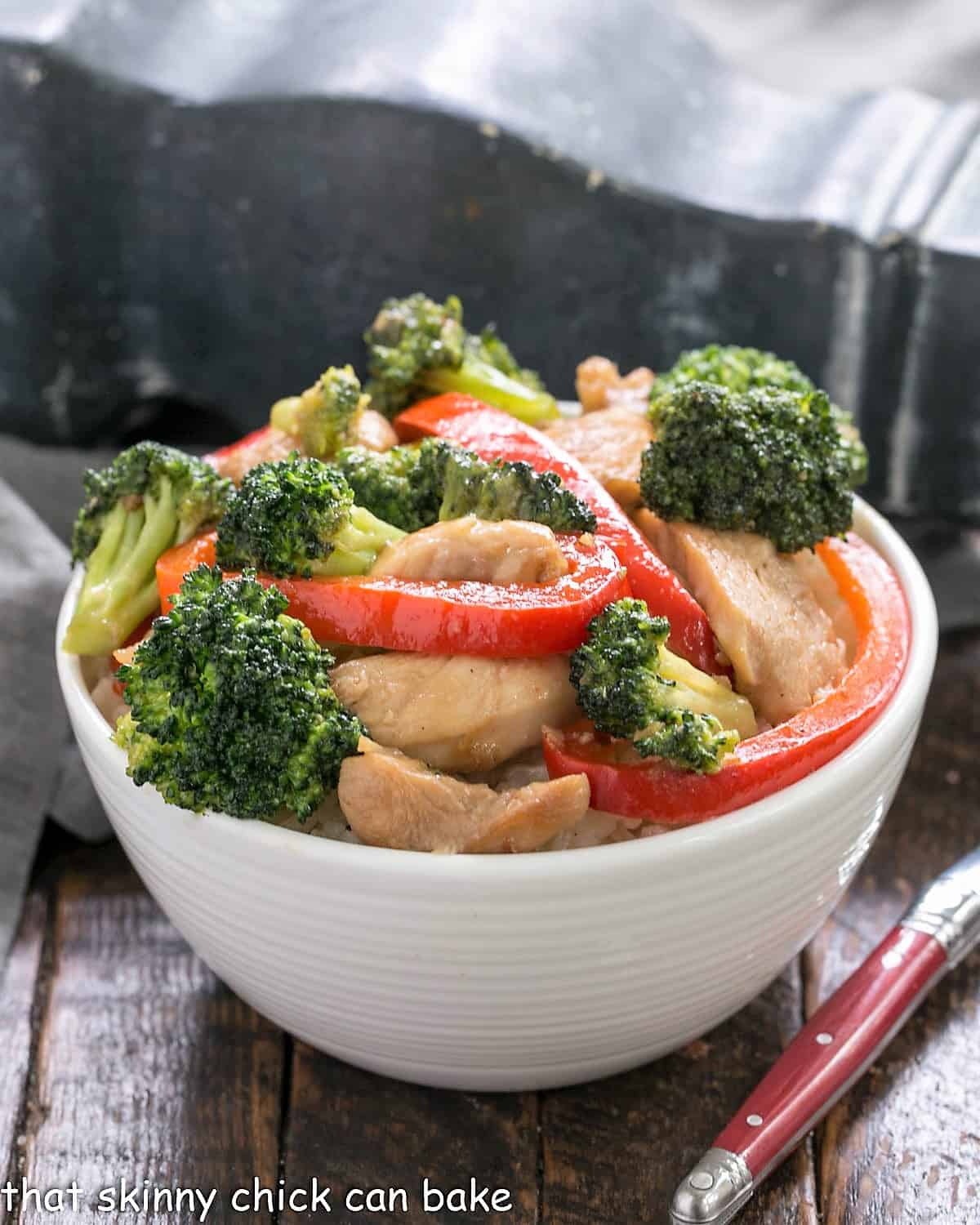 Bowl of chicken broccoli stir fry with a red handle fork.