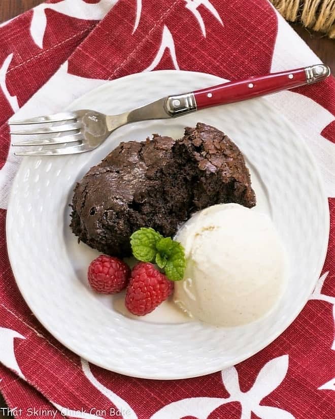 Slow Cooker Brownie Dessert - A delectable chocolate treat made in a slow cooker! Overhead view of a scoop of Slow Cooker Brownie Dessert on a white plate with a red handled fork.
