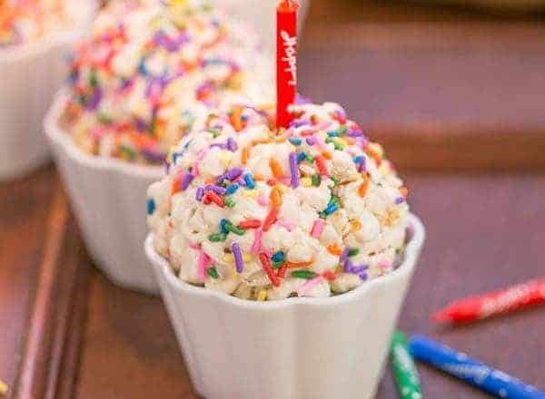Easy Marshmallow Popcorn Balls in white ramekins with birthday candles
