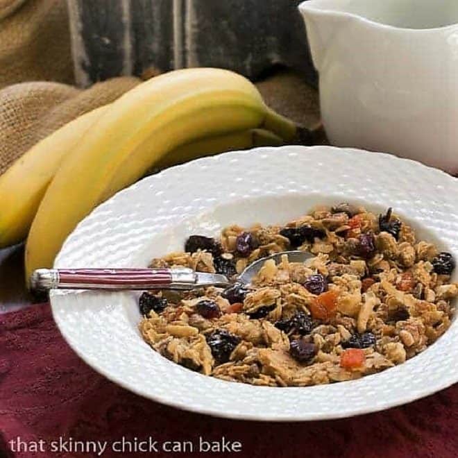 Pistachio Coconut Granola in a white cereal bowl with a red handled spoon.