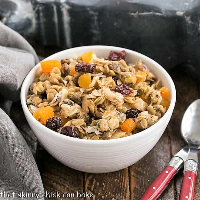 Bowl of cereal with spoon put on wood table near granola in glass