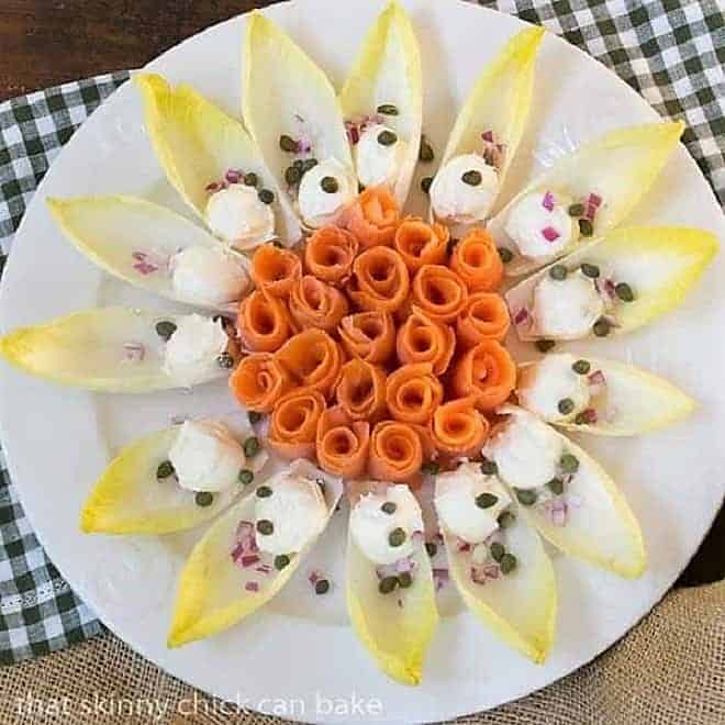 Smoked Salmon Roses with Endive and Creme Fraiche on a round white plate.
