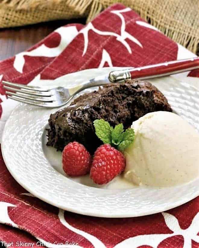 Slow Cooker Brownie Dessert on a white plate with a scoop of ice cream and fresh raspberries.