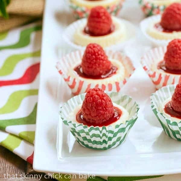 Mini Mascarpone Cheesecakes in red and green cupcake papers on a white tray.