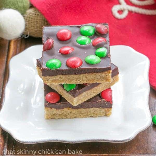 Candy Topped Toffee Squares stacked on a square white plate.