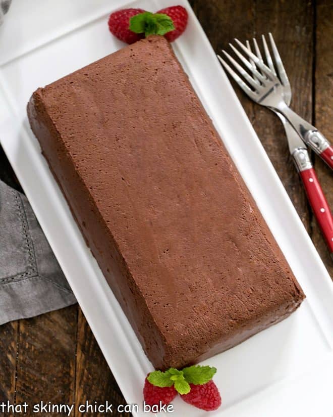 Chocolate Terrine with Raspberries and mint garnish on a white serving tray
