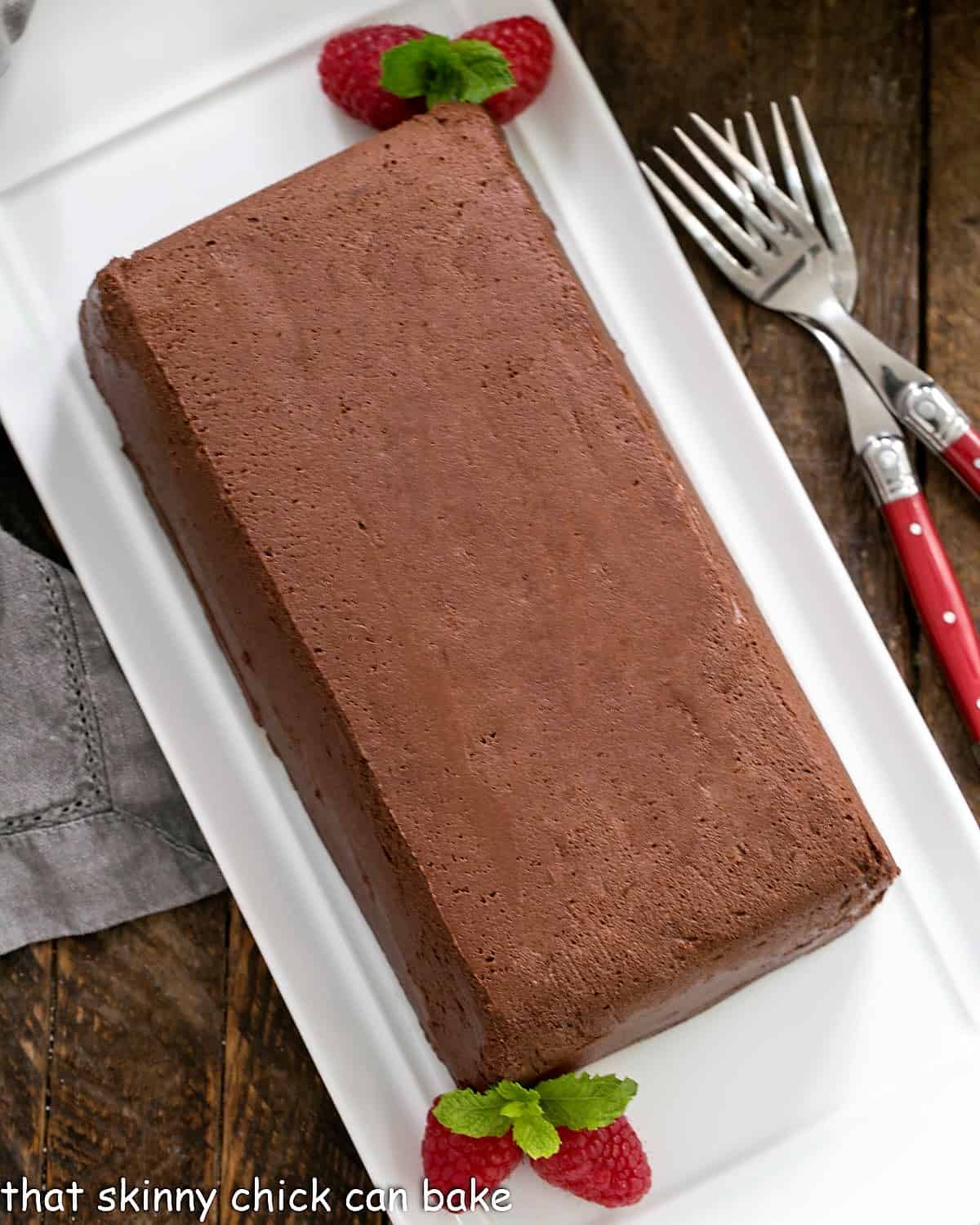 Chocolate Terrine with Raspberries and mint garnish on a white serving tray.