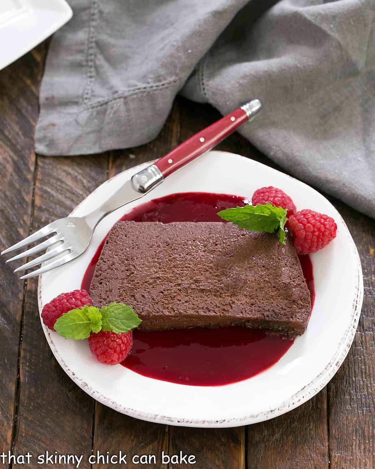 Overhead view of a Slice of Chocolate Terrine with Raspberry Sauce on a white plate with a red handle fork.