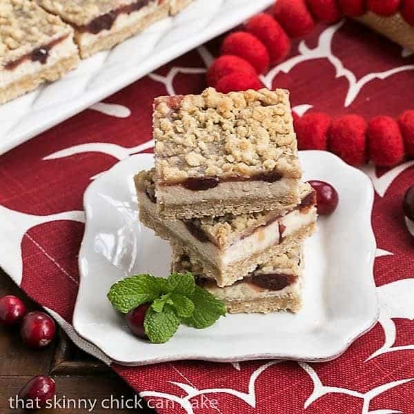 Cranberry Cheesecake Bars stacked on a white dessert plate