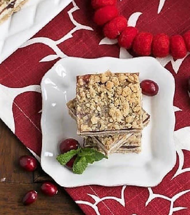 Cranberry Cheesecake Bars on a white dessert plate with fresh cranberries and mint