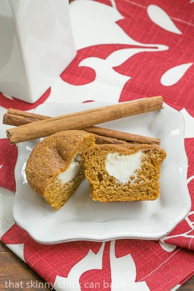 Overhead view of a Cream Cheese Filled Pumpkin Muffin on a white plate on a red and white floral napkin