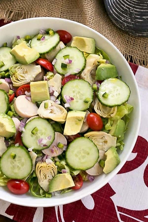 Hearts of Palm, Artichoke, Avocado and Butter Lettuce Salad overhead view in white serving bowl.