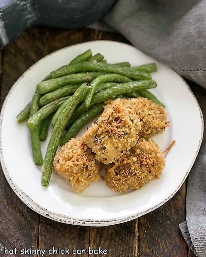 overhead view of homemade chicken nuggets on a round white plate with green beans.