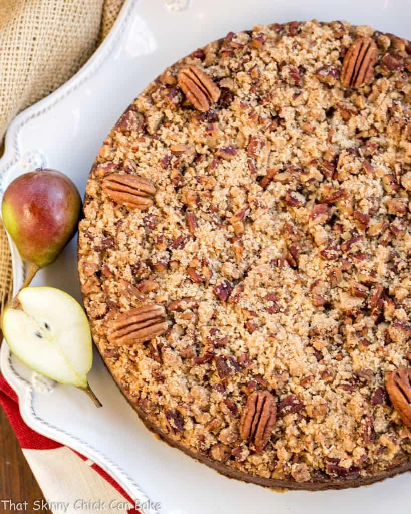 Pear Streusel Coffee Cake viewed from above on a white serving dish with small fresh pears