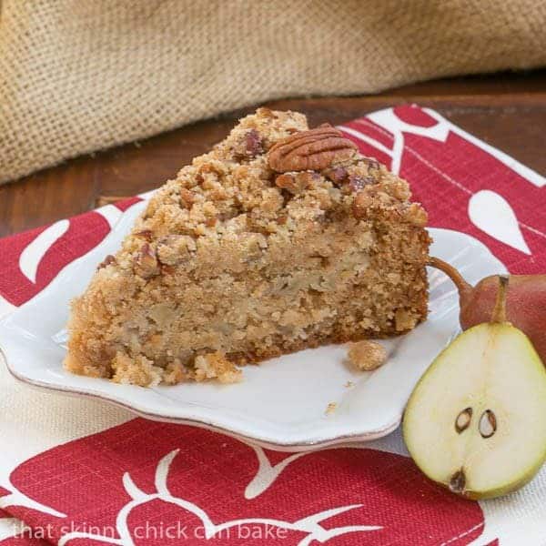 Slice of Pear Streusel Coffee Cake on a square white plate with a pear half