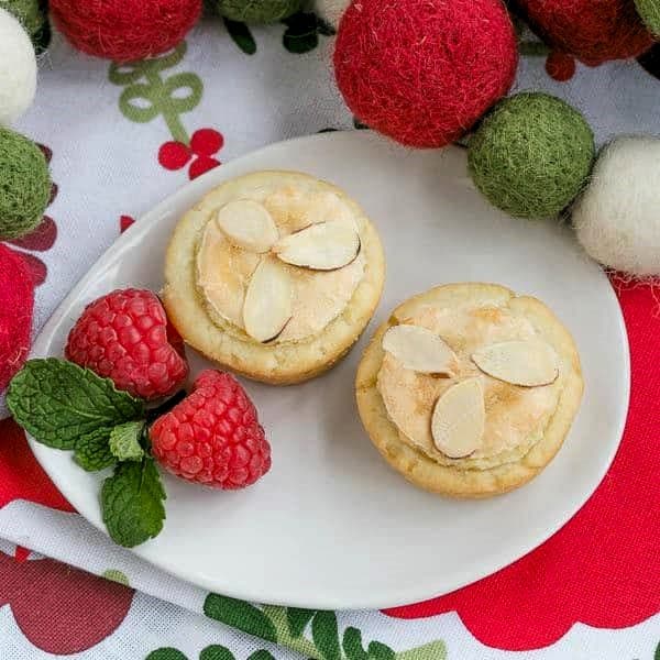 Overhead view of Almond Raspberry Tartlets on an oval white plate.