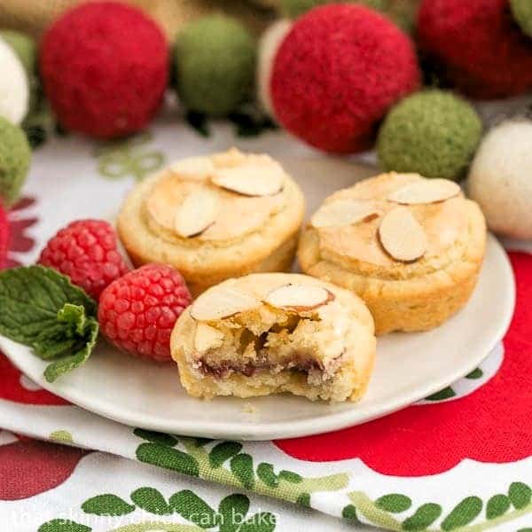 Almond Raspberry Tartlets on a white plate with interior exposed on one tart.